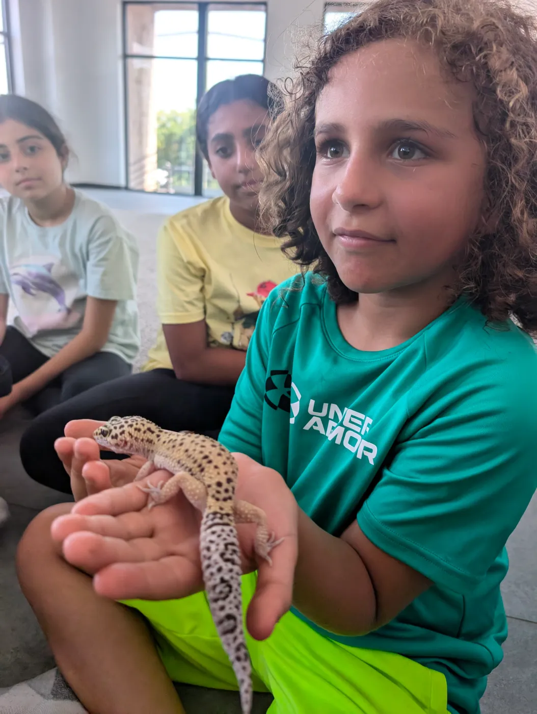 A child holding a lizard during an animal visit